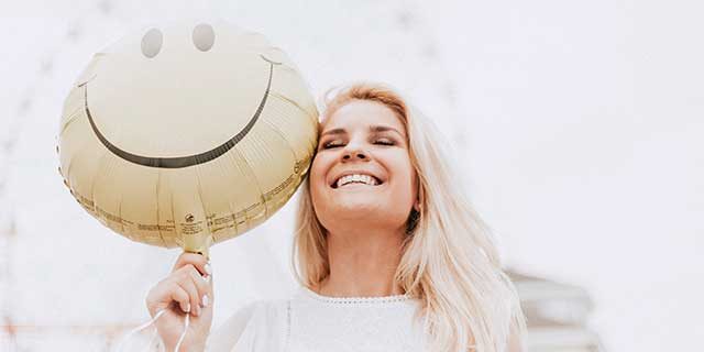Happy lady holding a smiling face balloon